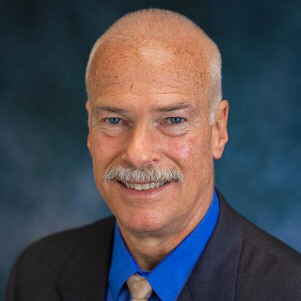 Smiling headshot photo of a man dressed in a suit named David Worley.