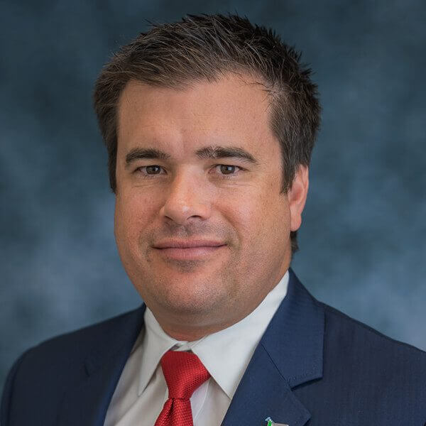 Smiling headshot photo of a man dressed in a suit named Tie Lasater.