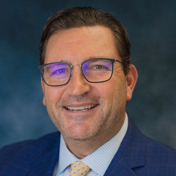 Headshot photo of older gentleman named Lee Dunlap wearing a suit and eye glasses.